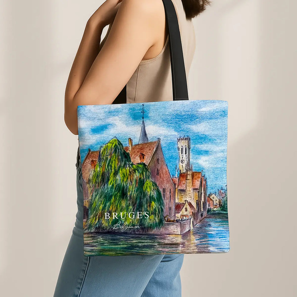 Tote bag with a scenic design of Bruges, held by a person.