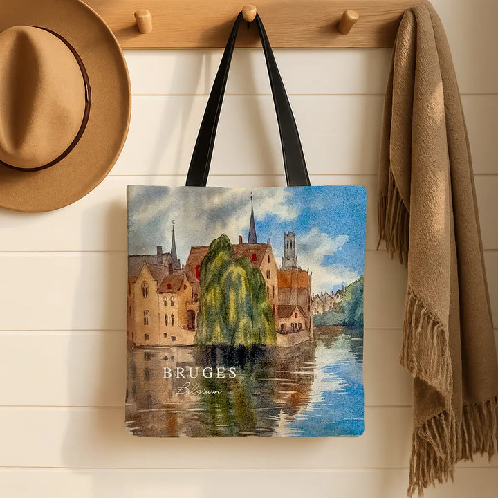 Tote bag with a scenic design of Bruges hanging on a wooden hook with a hat and scarf.