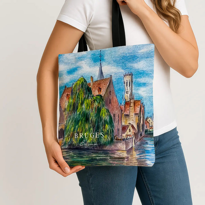 Person holding a tote bag with a painting of Bruges.