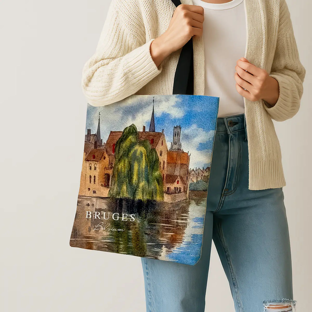 Person holding a tote bag with a scenic design of Bruges, Belgium.