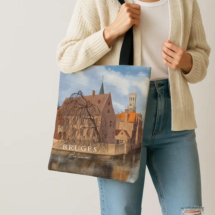Person holding a tote bag with a scenic design of Bruges, Belgium.