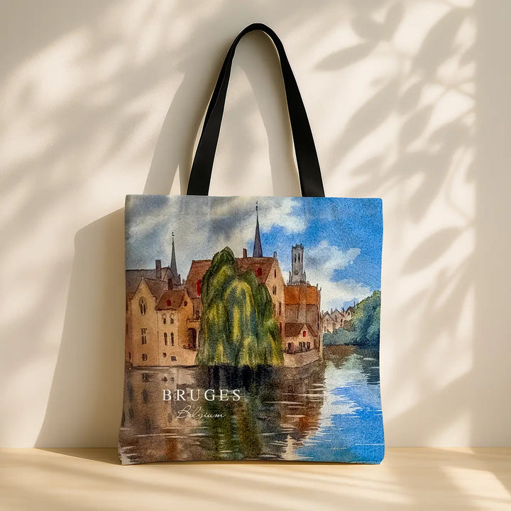 Tote bag with a scenic design of Bruges, featuring buildings and a river.