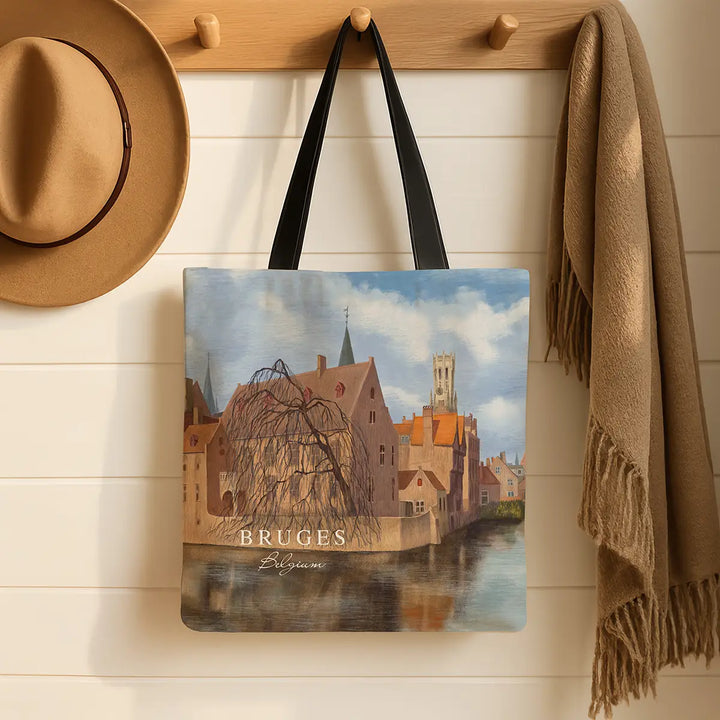 Tote bag with Bruges design hanging on a wooden hook with a hat and scarf.