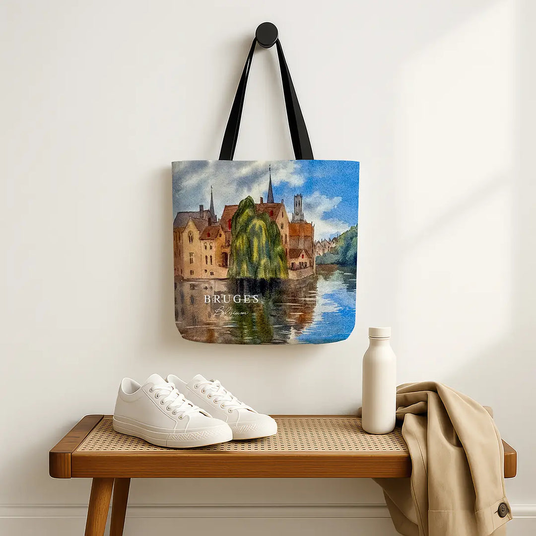 Tote bag with Bruges design hanging on a wall above a wooden bench with shoes and a bottle.