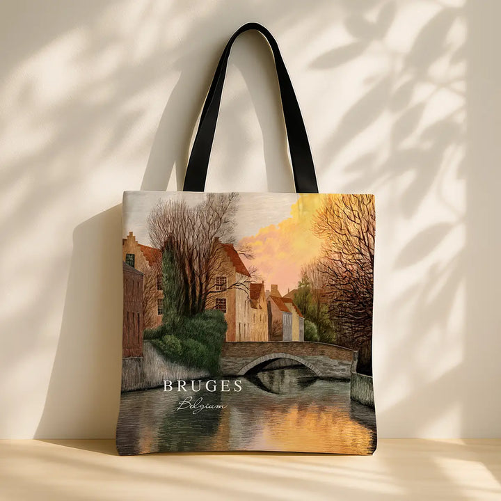 Tote bag with a scenic design of Bruges, featuring a bridge over water and buildings.