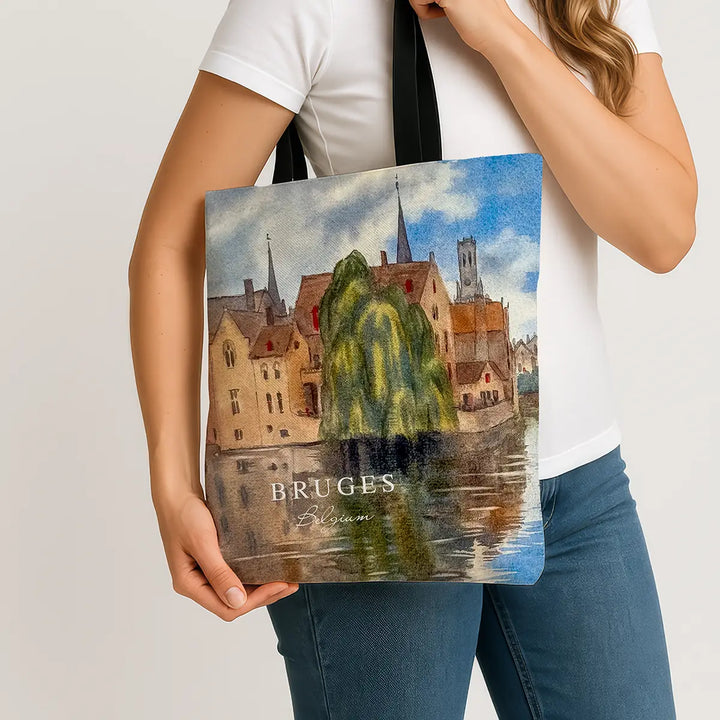 Person holding a tote bag with a scenic design of Bruges, Belgium.